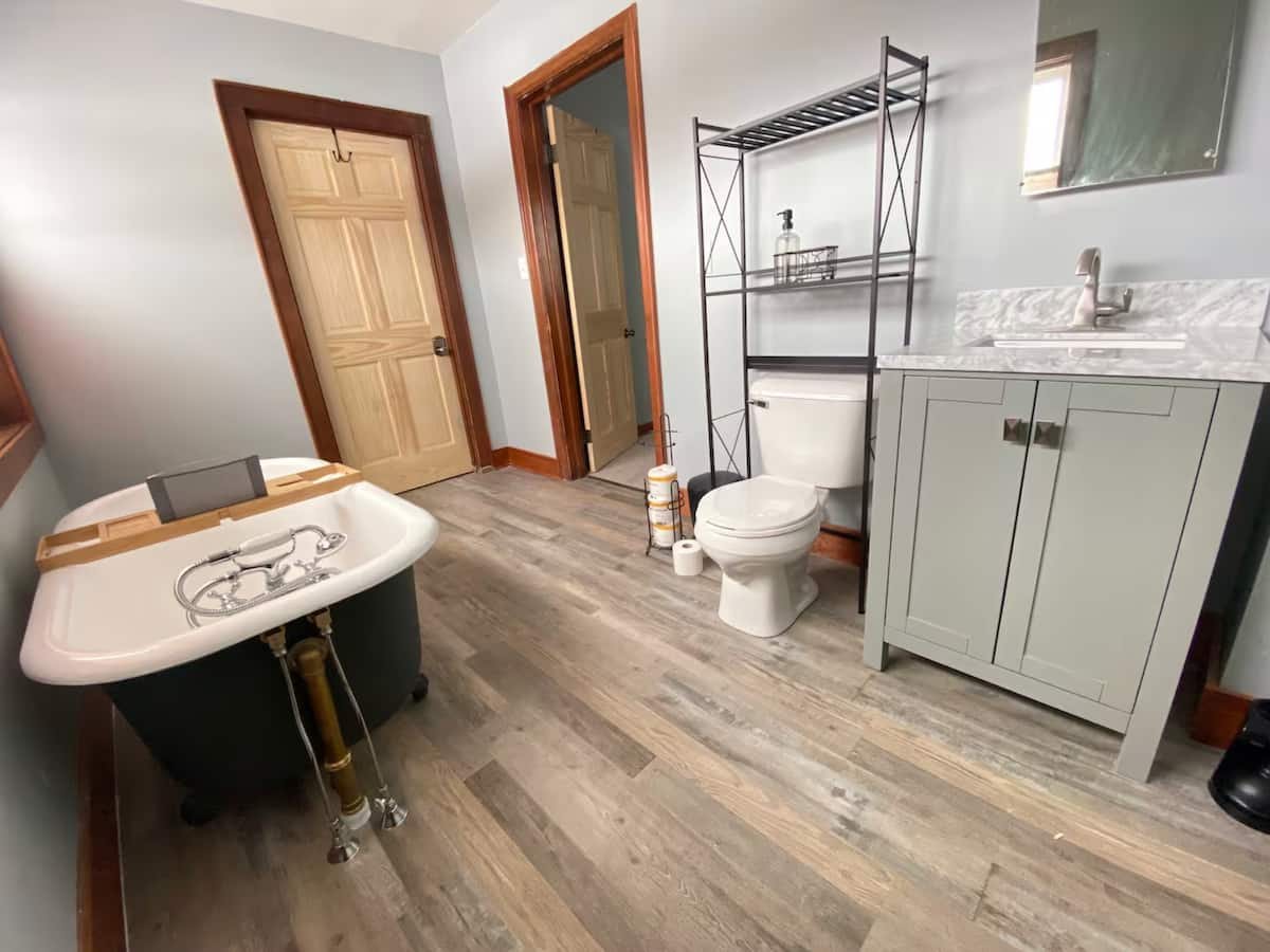 Full bathroom with freestanding tub, toilet, vanity, shelving, and original woodwork